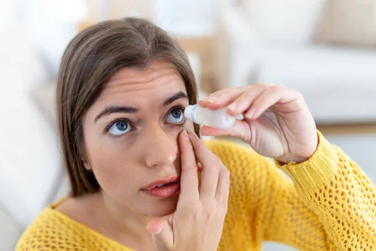 Woman putting eye drops into her eyes